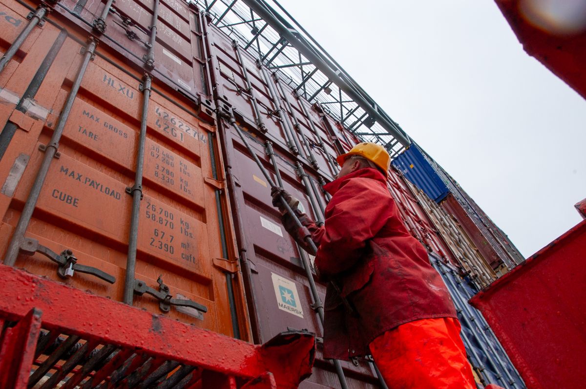 Worker securing cargo containers at a port
