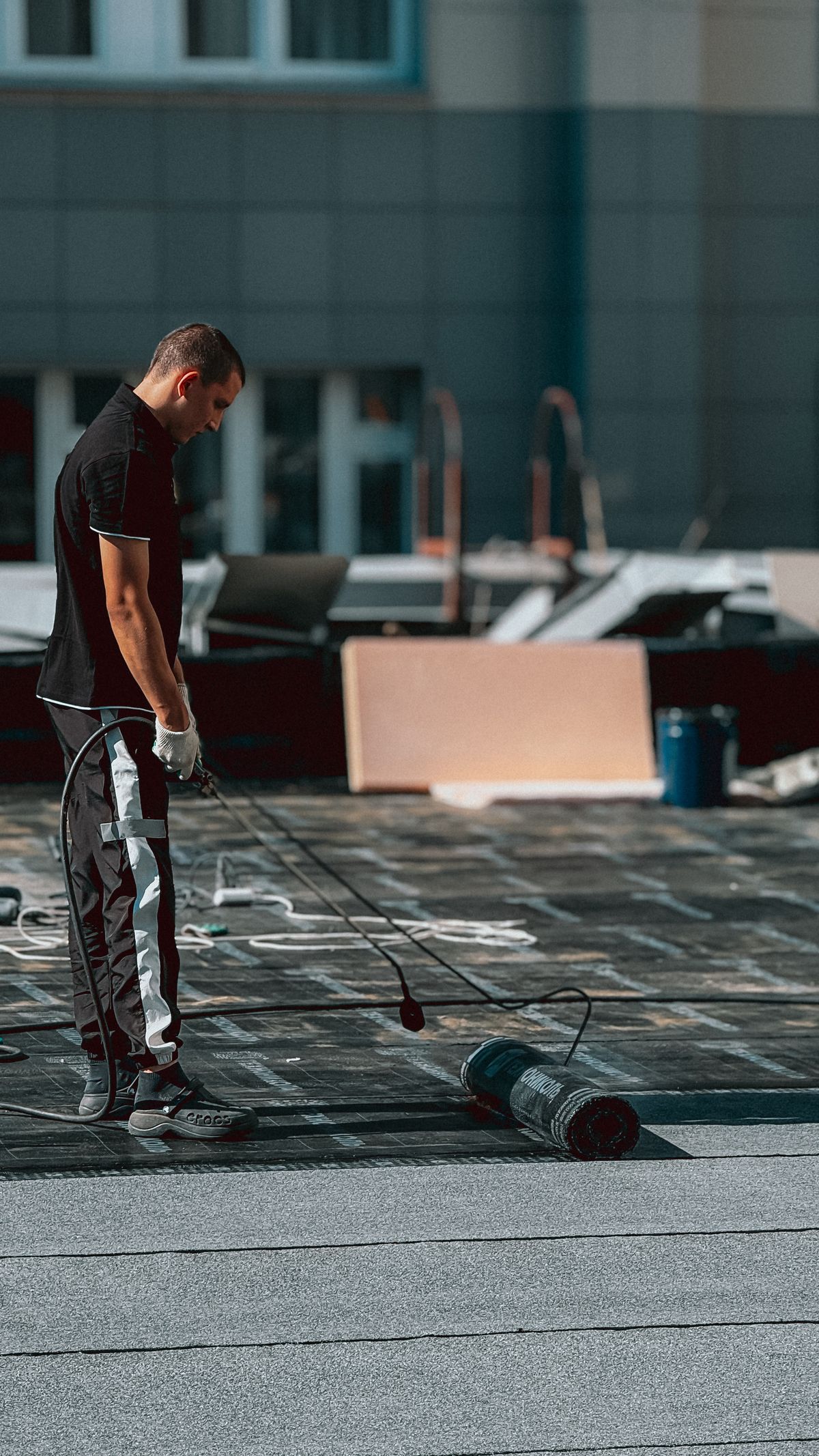 Worker applying a waterproofing coat on a rooftop